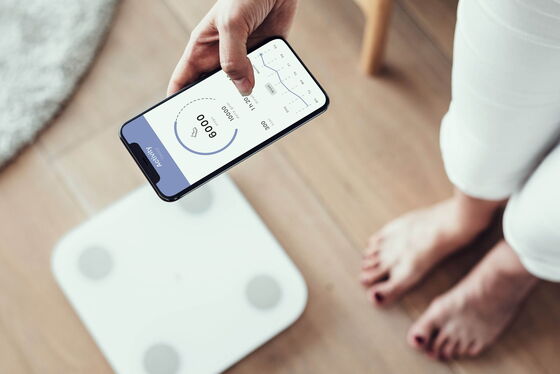 Eine Frau nutzt einen Aktivitäts-Tracker neben einer Waage zur Überwachung ihres Diabetes in der diabetologischen Praxis.