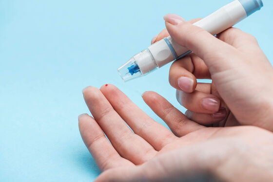 Eine Frau misst ihren Blutzucker mit einem Gerät, wichtig in der Diabetologie für Diabetes-Management.