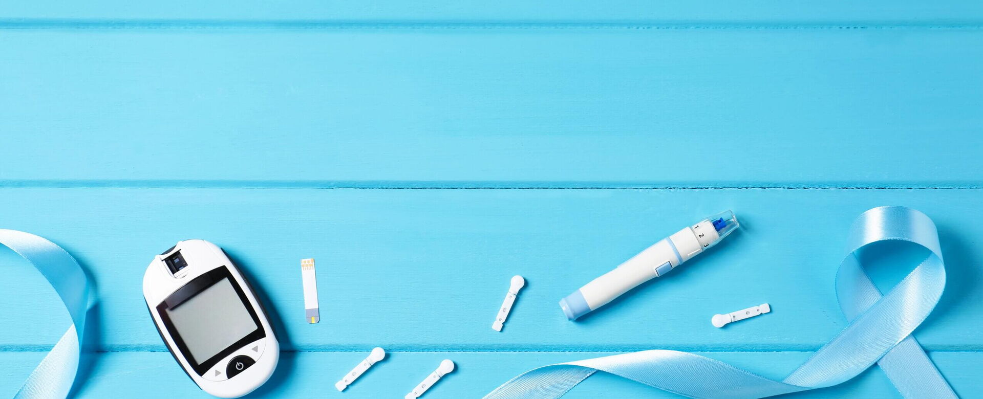 Medizinische Geräte zur Überwachung von Diabetes liegen auf einem blauen Hintergrund mit einer blauen Schleife.