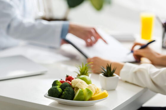 Ein Arzt gibt in einer diabetologischen Praxis gesunde Ernährungstipps zu Obst und Gemüse für Diabetes-Patienten.